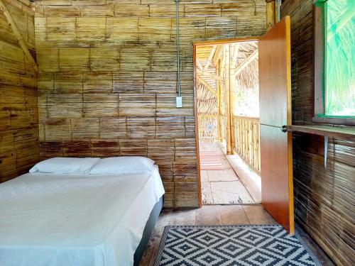 1 dormitorio con 1 cama en una pared de madera en Casa Estuario, en Buritaca