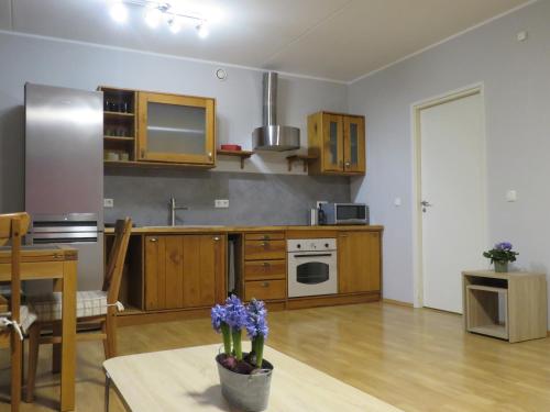 una cocina con armarios de madera y una mesa con flores púrpuras en Apartment Raatuse 82, Tartu kesklinnast 700m kaugusel, en Tartu