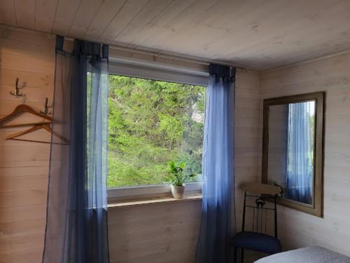 1 dormitorio con una ventana con cortinas azules y una silla en Kuusekoda, en Käina