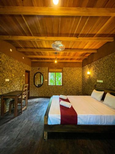 a bedroom with a bed and a table in it at Walawa Dreams Safari Resort in Udawalawe