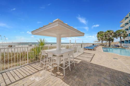 a table and chairs with an umbrella next to a pool at Sugar Sands Beachfront Hotel, a By The Sea Resort in Panama City Beach