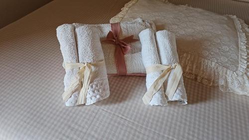 - un lit avec 2 serviettes blanches et un cadeau dans l'établissement S'Arrosa de Monti, à Villaputzu