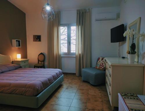 a bedroom with a bed and a chair and a window at S'Iscala apartment in Lanusei