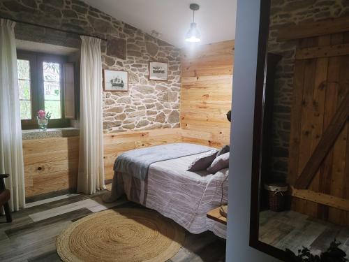 1 dormitorio con cama y pared de piedra en Casita vacacional 5 rutas en el rural Costa Da Morte, en A Coruña