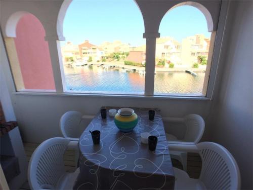 une table avec des chaises et une fenêtre avec vue sur l'eau dans l'établissement T3+Cabine avec Piscine, Parking - Port Barcarès - FR-1-81-247, au Barcarès