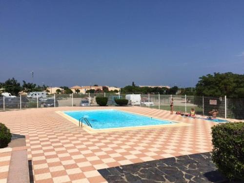 une grande piscine avec du carrelage et une clôture dans l'établissement Grand T3 avec terrasse, piscine et parking près de la plage - FR-1-81-242, au Barcarès