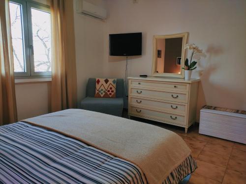 a bedroom with a bed and a dresser with a mirror at S'Iscala apartment in Lanusei