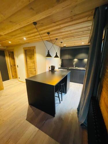 - une cuisine avec un îlot noir dans la chambre dans l'établissement Romy appartement centre village, à Megève