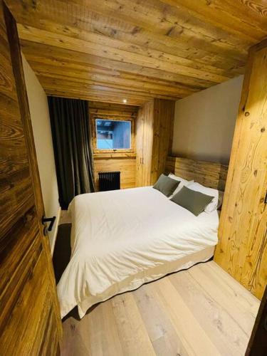 a large white bed in a room with wooden walls at Romy appartement centre village in Megève