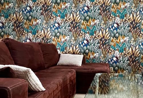a living room with a couch and a floral wallpaper at Apartamenty Villa Fiori - Wyspa Sobieszewska in Gdańsk