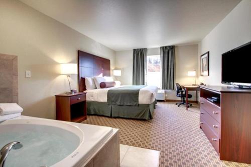 a hotel room with a bed and a bath tub at Cobblestone Hotel & Suites - Knoxville in Knoxville