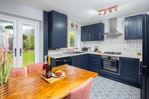 Whiteoak House في بولتون: مطبخ مع دواليب زرقاء وطاولة خشبية