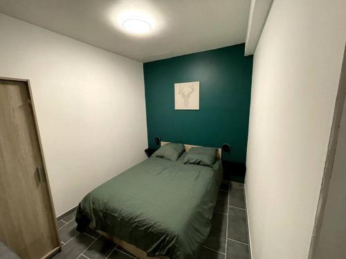 - une chambre dotée d'un lit avec un mur vert dans l'établissement Jolie T2 au coeur des collines, à Les Veyrières