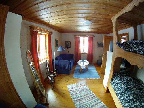 a living room with a wooden ceiling and a room with a couch at Rustika strandstugor utanför Rättvik in Rättvik