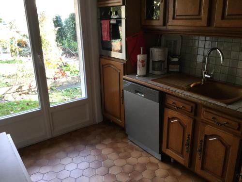 - une cuisine avec évier et lave-vaisselle à côté d'une fenêtre dans l'établissement Appartement fond de jardin rez-de-chaussée, à Palaiseau