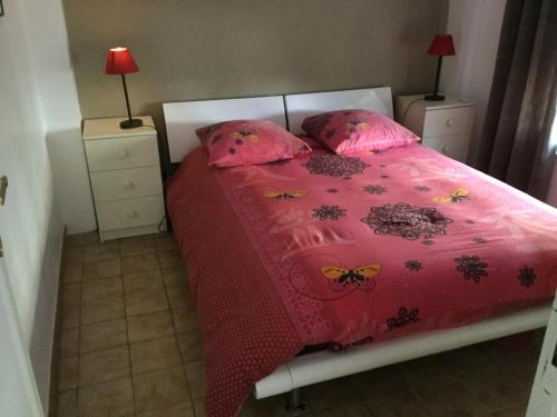 - un lit avec une couette rose et des papillons dans l'établissement Appartement fond de jardin rez-de-chaussée, à Palaiseau