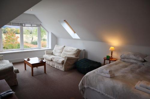 1 dormitorio con cama, sofá y ventana en Chauffeurs Cottage, en Comrie