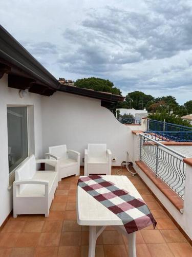 einen Balkon mit weißen Stühlen und Tischen auf einem Gebäude in der Unterkunft casa montauro in Stalettì