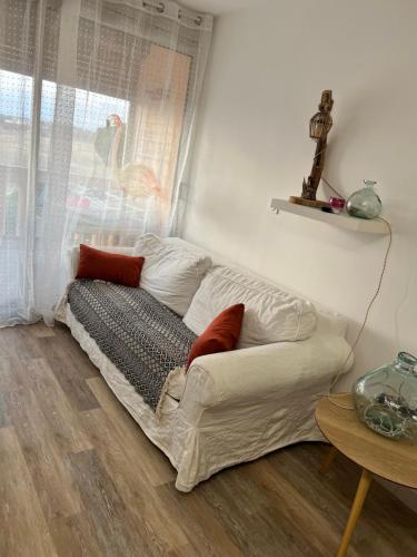 um sofá branco sentado num quarto com uma janela em T1 bis avec piscine em Canet-en-Roussillon