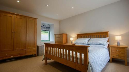 a bedroom with a wooden bed with two night stands and two cabinets at Earnbank in Lochearnhead
