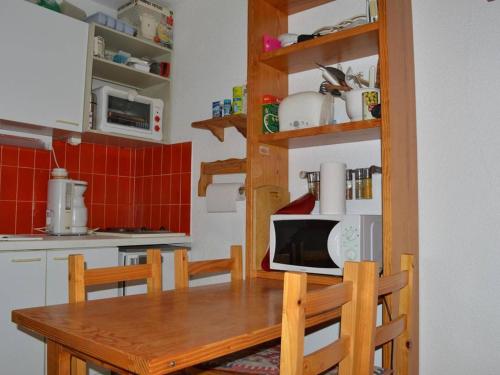 une cuisine avec une table en bois et un micro-ondes dans l'établissement Appartement cosy au Port d'Argelès, 2 pièces/cabine, 6 couchages, proche mer, loggia, ménage inclus - FR-1-225-453, à Argelès-sur-Mer