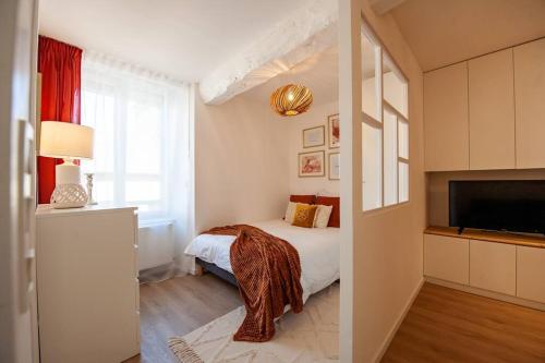 two images of a bedroom with a bed and a television at Appartement cocoon dans maison du XVIIème siècle in Fougères