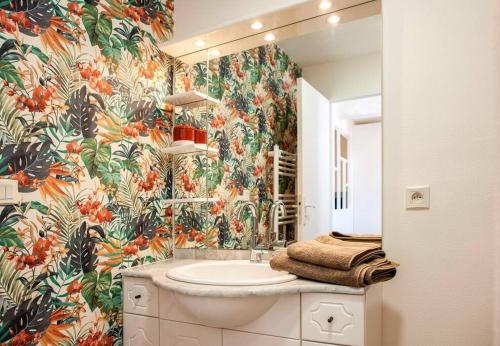 baño con lavabo y papel pintado con motivos florales en Appartement cocoon dans maison du XVIIème siècle, en Fougères