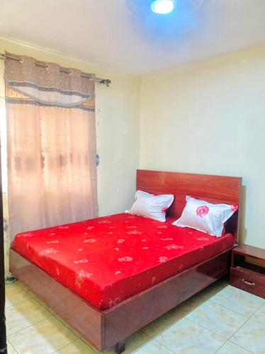 a red bed in a room with a window at APEX ANNEX Guest Facility in Buea