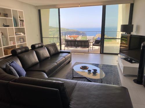a living room with a leather couch and a television at Gozo Dwejra Views in San Lawrenz