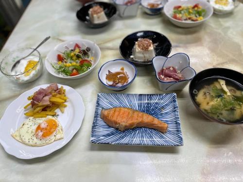 einen Tisch mit Teller mit Lebensmitteln und Schüsseln mit Lebensmitteln in der Unterkunft Ryokan Warajisha - Vacation STAY 62566v in Goto