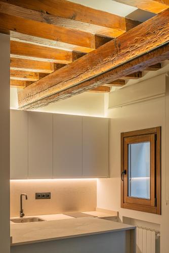 a kitchen with white cabinets and a wooden ceiling at El Clavel de la Plaza in Cuenca