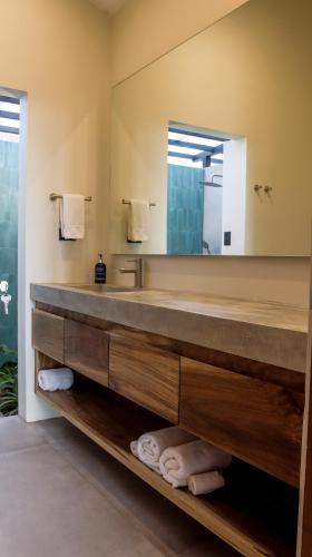 a bathroom with a large mirror and a sink at Surf Synergy All-Inclusive Surf and Wellness Retreat in Jacó