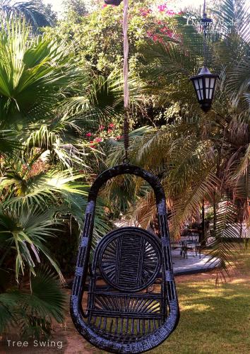 a tree swing in a park with palm trees at Dreamland by Nature's Abode® Villas in Ahmedabad