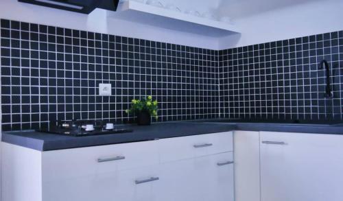 a kitchen with white cabinets and a black tile wall at Mado Coliving - Studio Appart, Chambre coin cuisine, Chambre in Douala