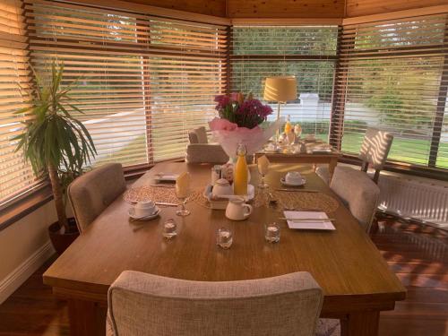 a wooden table in a room with chairs and windows at Robin Hill Bed and Breakfast in Curracloe