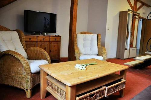 ein Wohnzimmer mit 2 Stühlen, einem Tisch und einem TV in der Unterkunft Penzión Rosenau in Rožňava