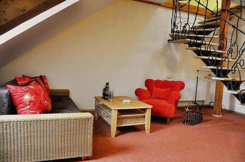a living room with a red chair and a table at Penzión Rosenau in Rožňava