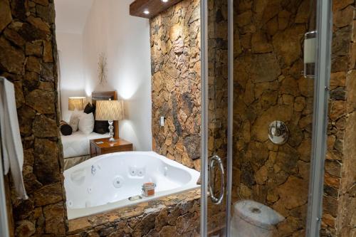 uma banheira na casa de banho com uma parede de pedra em Sueños Resort em El Porvenir
