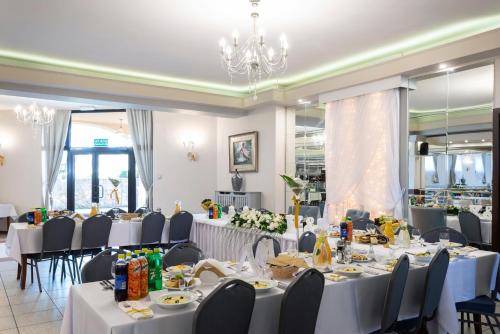 jadalnia z białymi stołami i krzesłami w obiekcie Hotel Victoria w mieście Olkusz