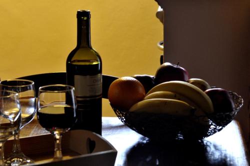 a bottle of wine and a bowl of fruit on a table at Antica Dimora in Monteroni dʼArbia