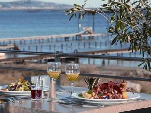 une table avec deux assiettes de nourriture et des verres de vin dans l'établissement Maison mitoyenne duplex avec terrasse, garage et parking, proche plage, équipée pour 4 à 6 personnes - FR-1-326-385, à Marseillan