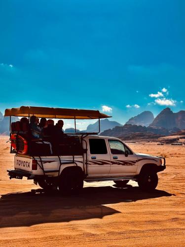 a white truck with people riding in the desert at RUM FLORAA LUxURY CAMP in Wadi Rum