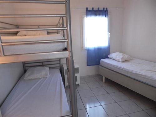 une chambre avec deux lits superposés et une fenêtre dans l'établissement Maison 3 pièces pour 5, grand jardin, terrasse, parking privé, proche plages - Marseillan - FR-1-326-448, à Marseillan
