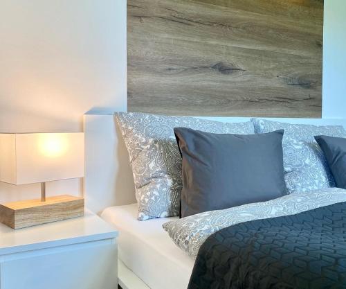 a bedroom with a bed with blue pillows and a lamp at Apartmány DOME in Doksy