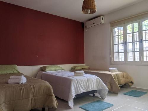 Un dormitorio con dos camas y una pared roja. en Roque 4047, en San Juan