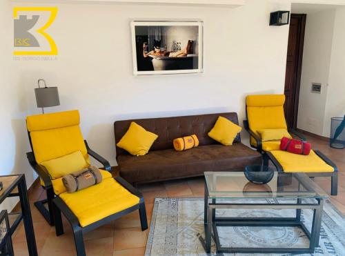 a living room with yellow chairs and a brown couch at BB Bis in Candelo