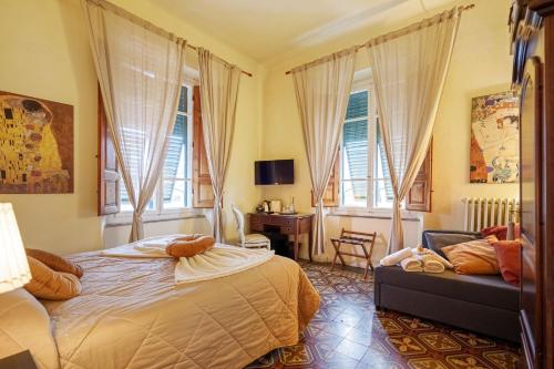 um quarto com uma cama, uma cadeira e janelas em Villa San Donato B&B em Lucca