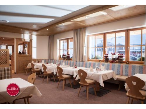 a dining room with tables and chairs and windows at Hotel Nassfeld in Sonnenalpe Nassfeld