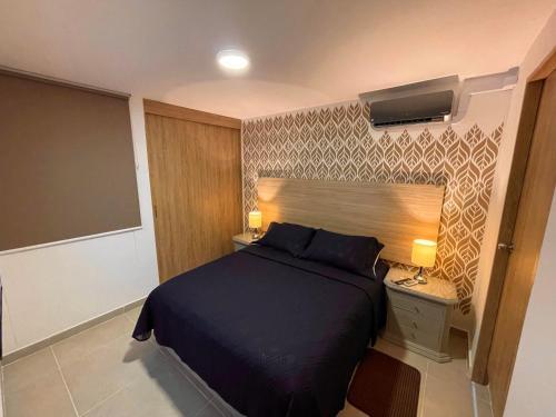 a bedroom with a large bed and a night stand with a lamp at Apartamento en Cali Inn tropical CLO in Cali