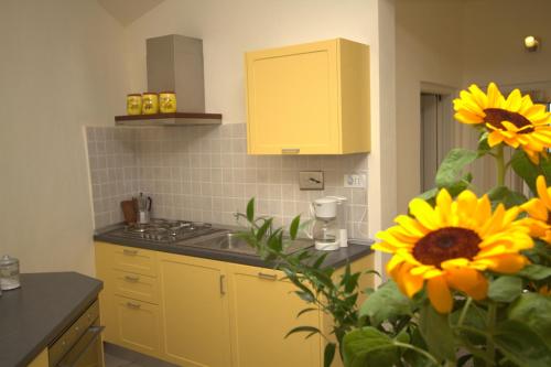 a kitchen with yellow cabinets and a bouquet of sunflowers at Appartamenti Chiarina in Dolcedo